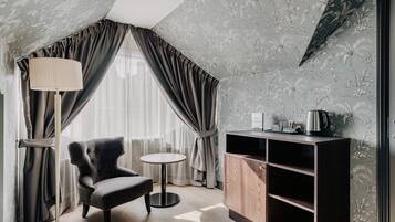 Una habitación con un sillón oscuro, una mesita redonda pequeña, una lámpara de pie y un aparador de madera con estantes.