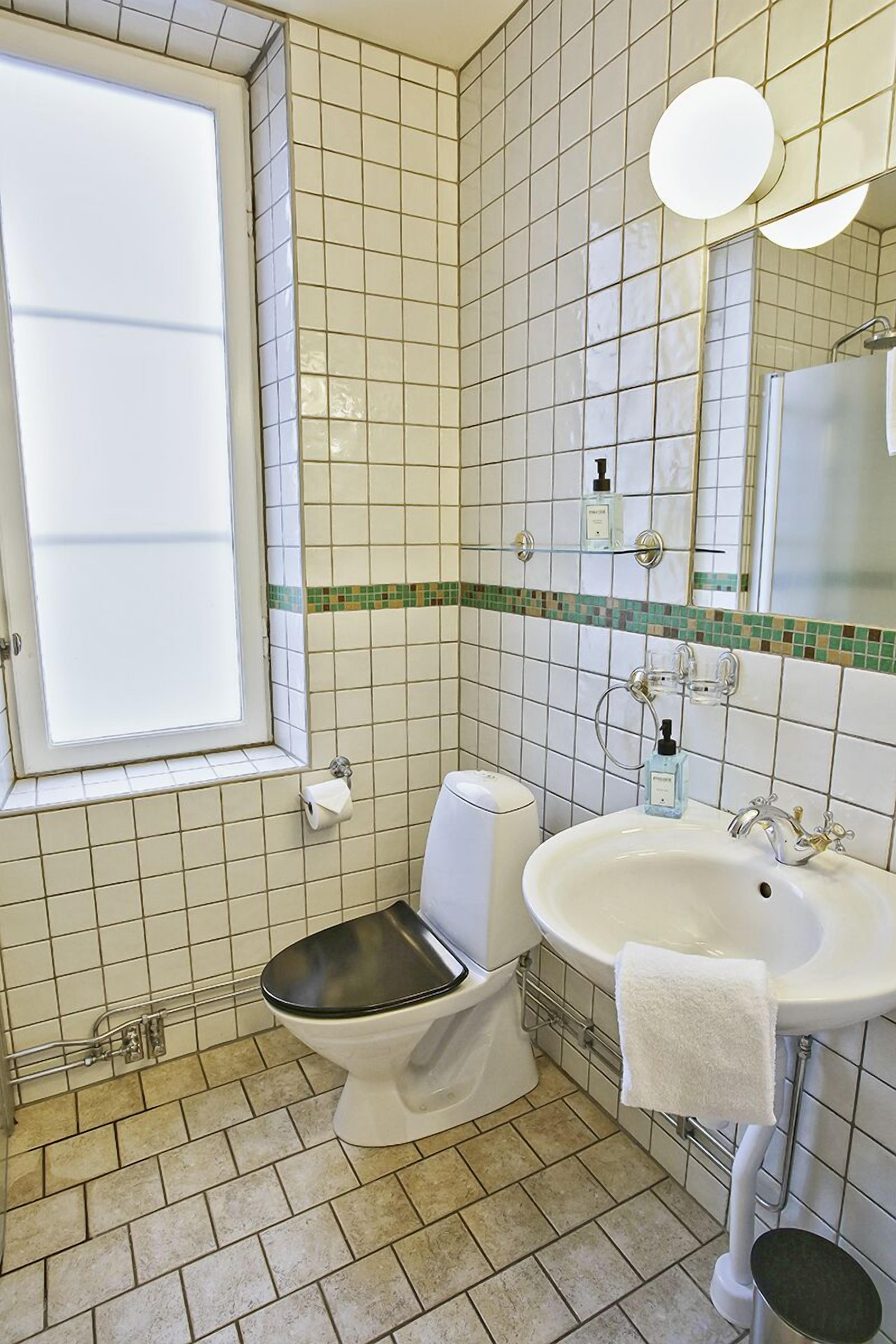 A bathroom with a toilet, sink, and mirror.