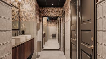 A narrow hallway with a vanity area on the left, a mirror, and a door on the right.