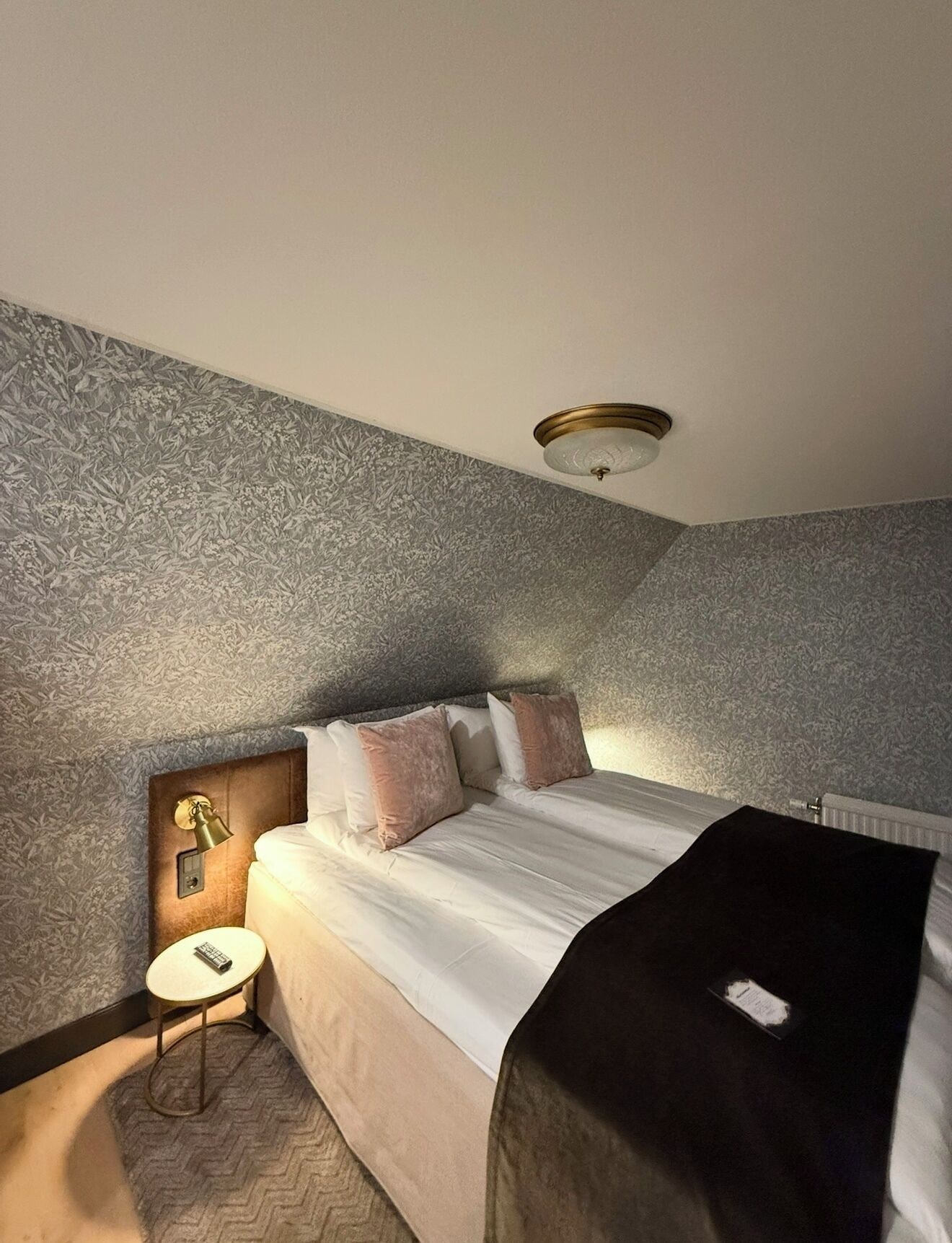 A bedroom with a bed, a nightstand, a lamp, and a textured wall.