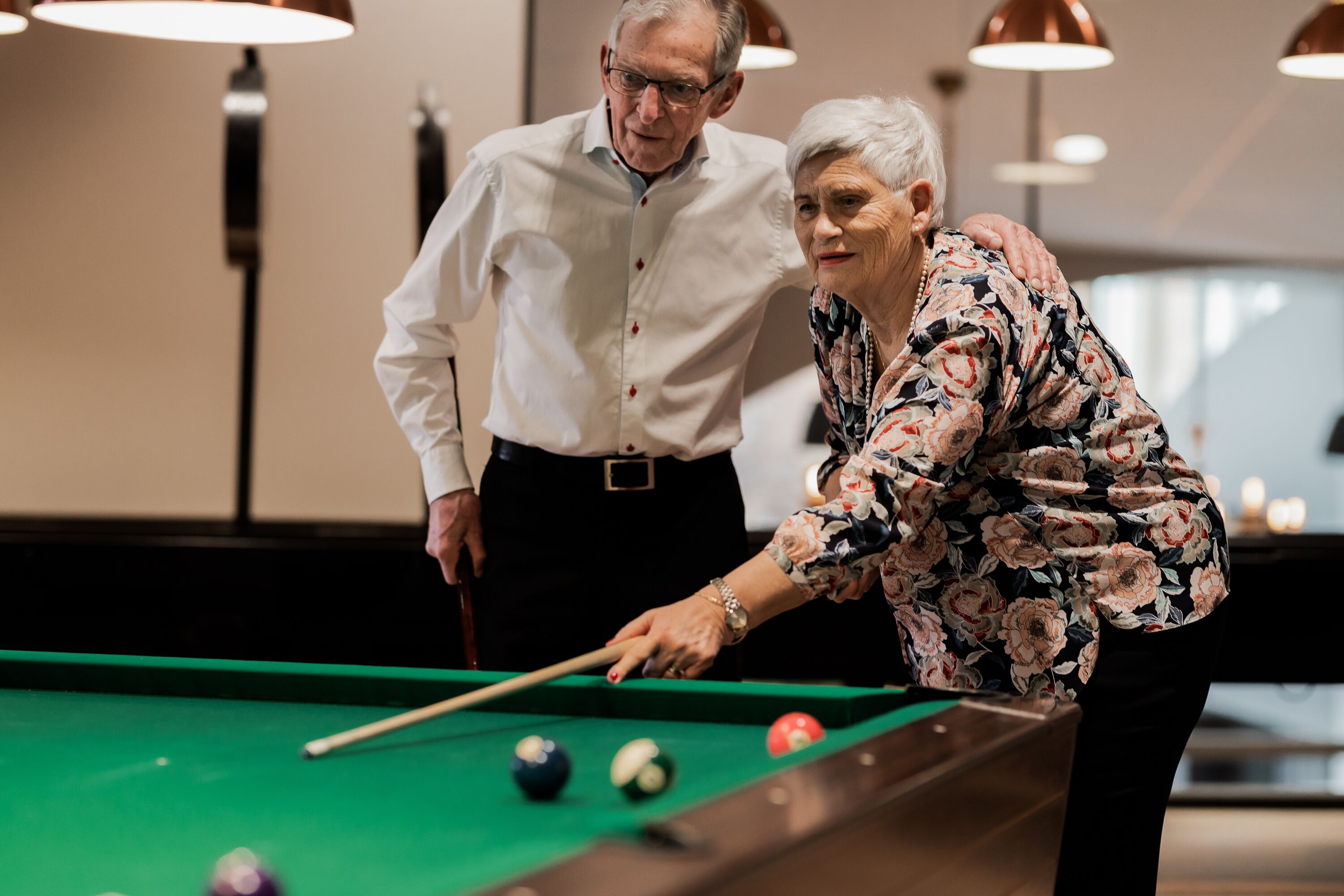 A pool table with balls and two people playing.