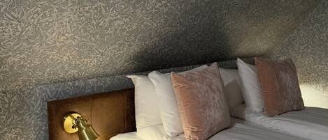 A hotel room with a bed, a nightstand, a lamp, and a remote control on a small table.