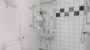 Ett modernt badrum med ett vitt handfat, en spegel och en handdukshängare.