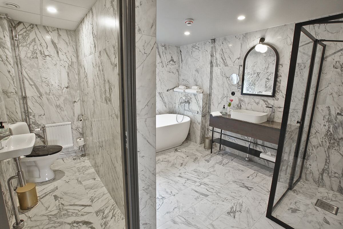 A bathroom with a marble floor, a bathtub, a sink, and a toilet.