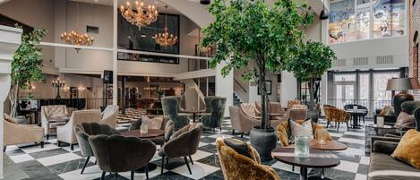 A spacious lobby with a checkered floor, multiple seating areas, and a large chandelier.