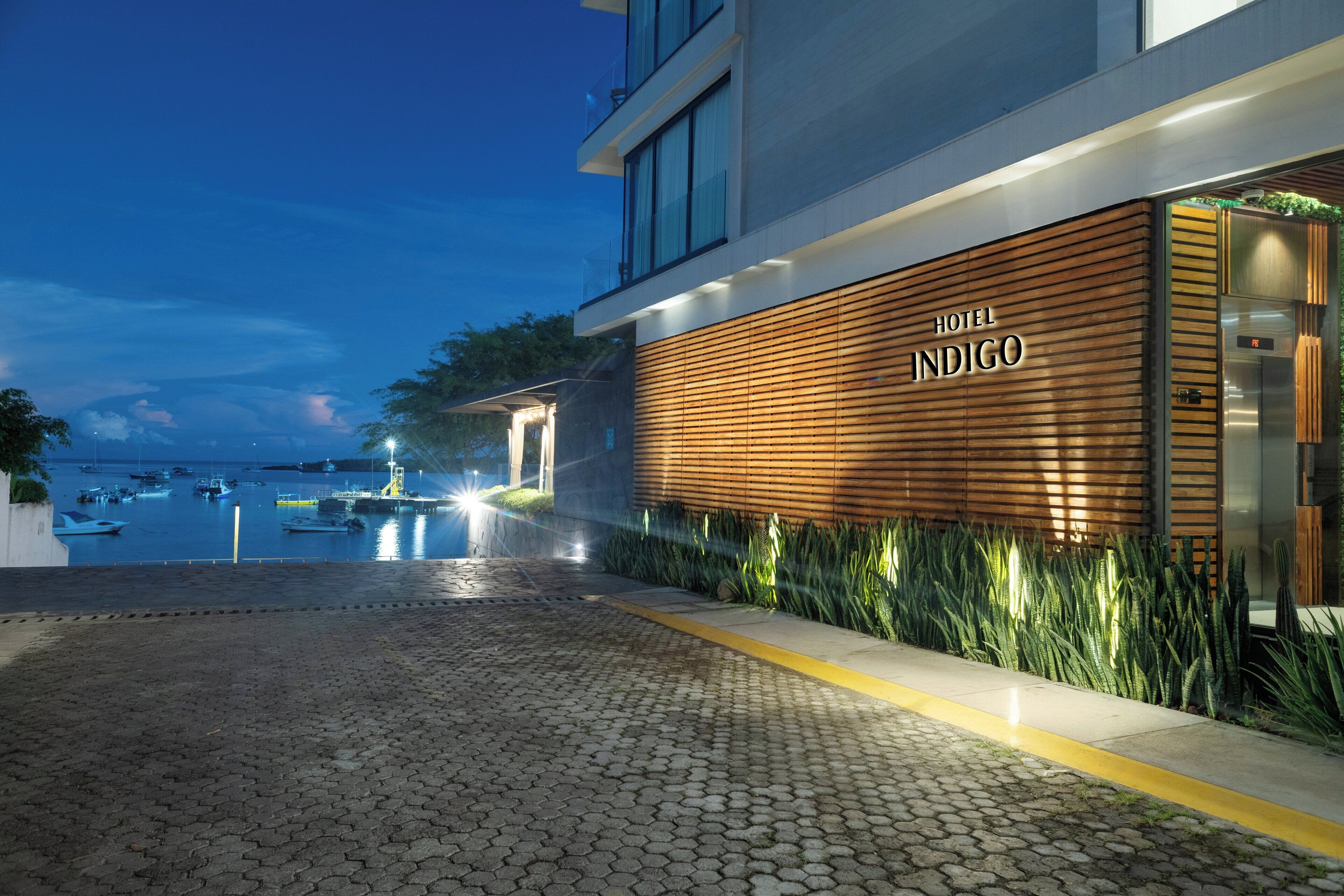 A modern hotel entrance with a wooden facade and a view of the marina.