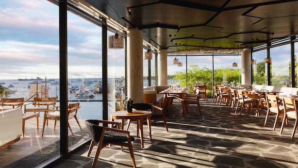 Un vaste espace extérieur aménagé pour les repas, offrant une vue sur le port et les bateaux.