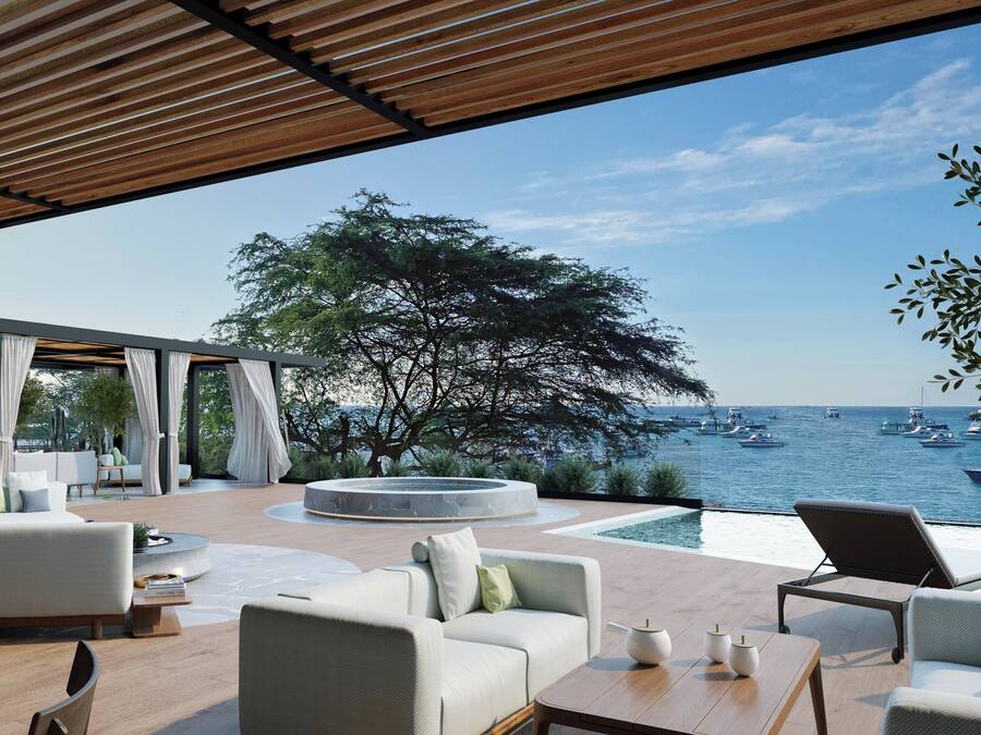 A modern outdoor lounge area with seating, a pool, and a view of the sea with boats.
