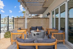 An outdoor seating area with wicker furniture and a central fire feature.
