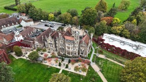 A large, historic building with a courtyard, surrounded by lush greenery and a parking area. - Oakley Court (Windsor)
