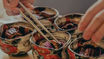 A person using chopsticks to eat from a bowl with a floral pattern.