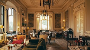 A spacious room with a large window, elegant furniture, and a chandelier. - Oakley Court (Windsor)