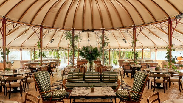 A spacious tented dining area with wooden furniture and hanging plants. - Oakley Court (Windsor)