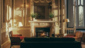 A grand room with a fireplace, ornate furniture, and a large window. - Oakley Court (Windsor)