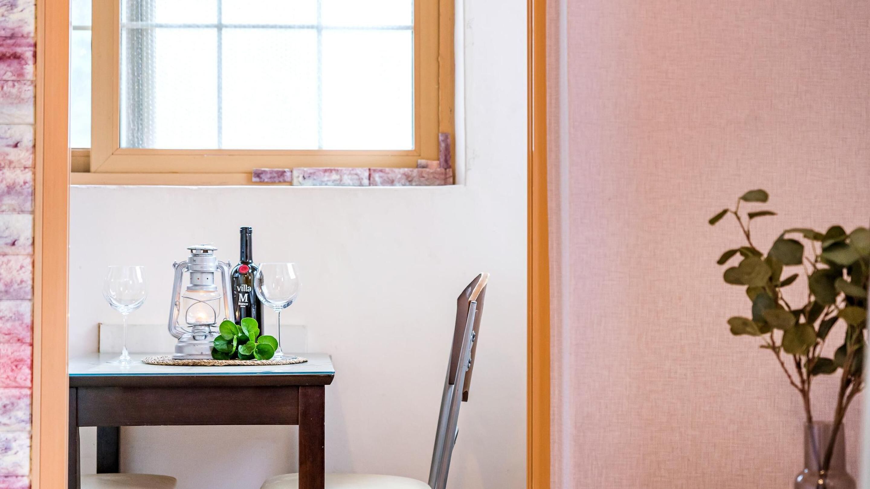 Una mesa con dos copas de vino, una botella y un farol.