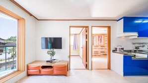 A modern kitchen with blue cabinets, a wooden countertop, and a TV mounted on the wall. - Gangchon Pine Hill Pension (Chuncheon)