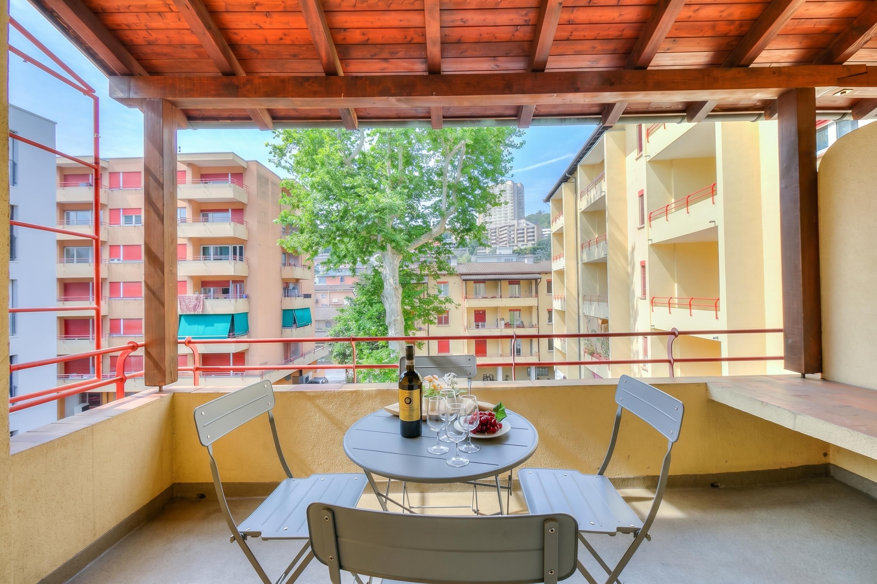 A balcony with a table, chairs, a bottle, and glasses.