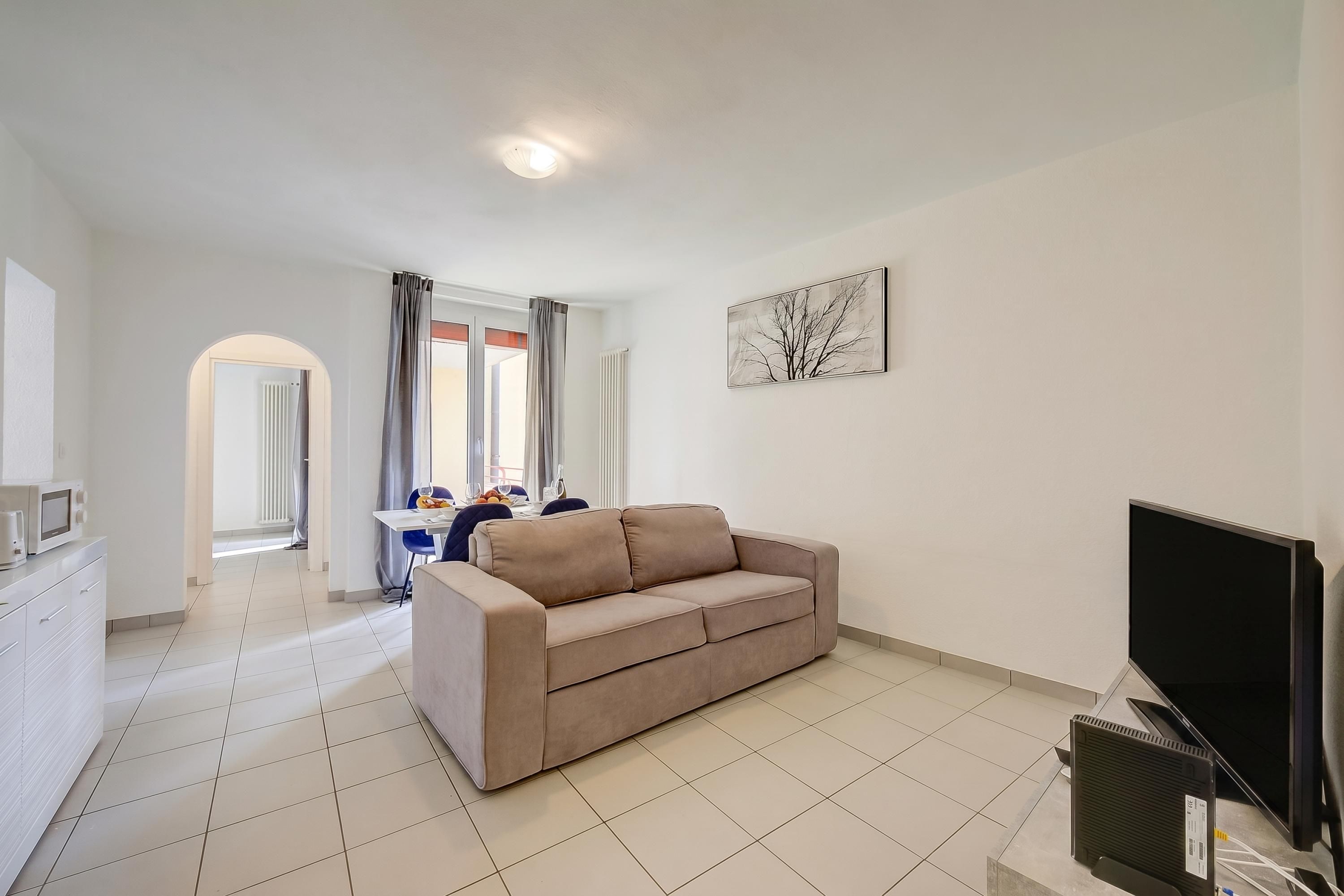 A living room with a sofa, a flat-screen TV, and a radiator.