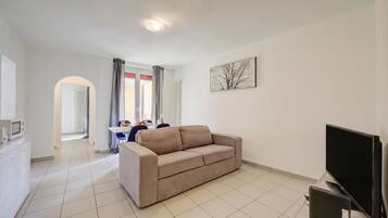 A living room with a sofa, a flat-screen TV, and a radiator.