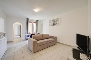 A living room with a sofa, a flat-screen TV, and a radiator.