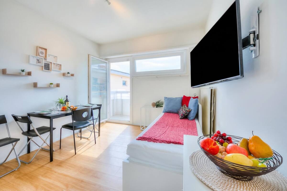 Una habitación moderna con una cama, un escritorio y un televisor.