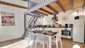 Eine moderne Küche mit Holzboden, einer Treppe und einem Essbereich mit weißen Stühlen.