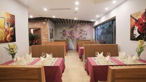 A restaurant with wooden booths, red tablecloths, and floral centerpieces. - Oriana Hotel 2 (Hanoi)