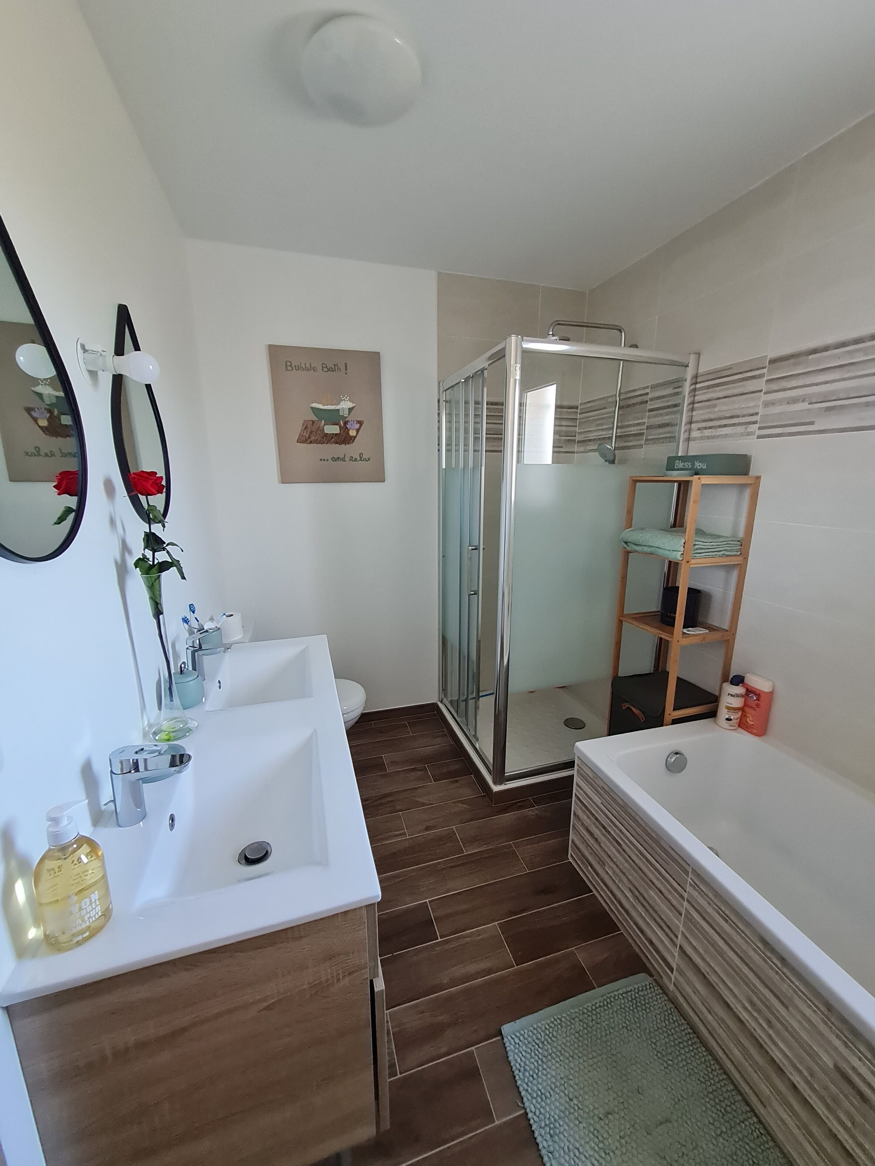 Un bagno moderno con lavandino bianco, cabina doccia in vetro e mobile bagno in legno.