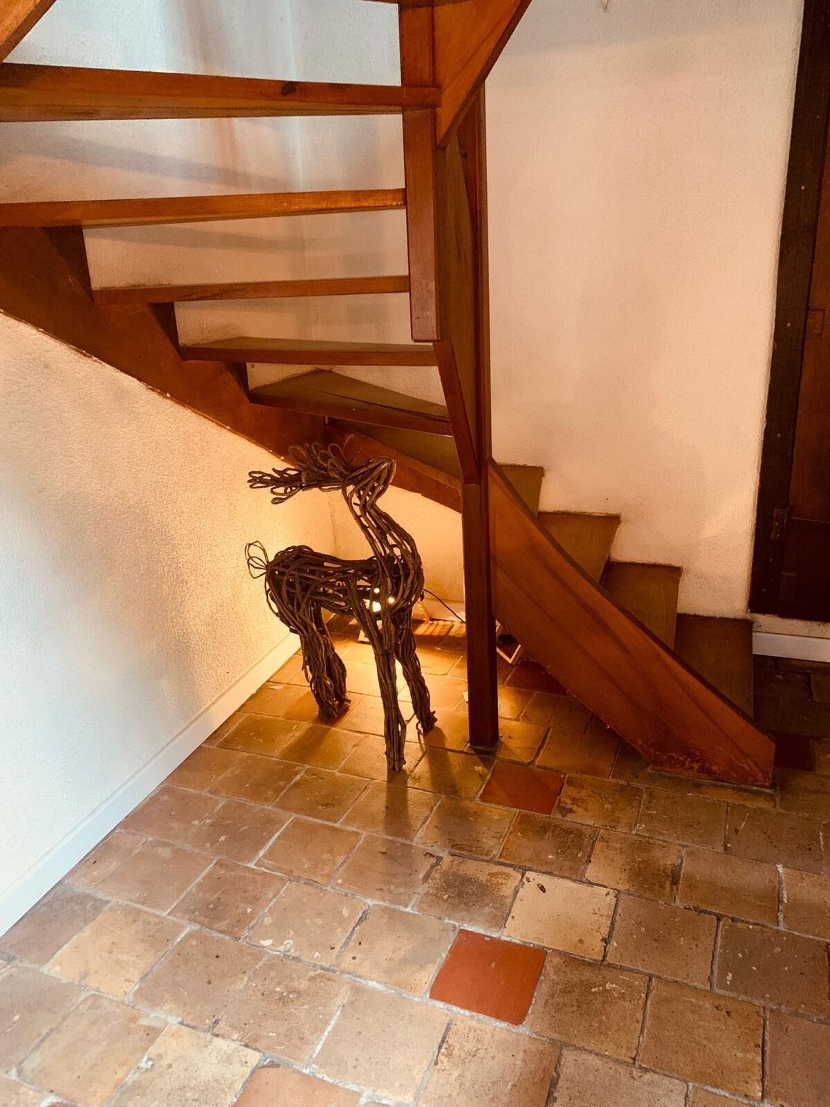 A staircase with a wooden handrail and a decorative deer sculpture on the floor.