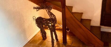 A staircase with a wooden handrail and a decorative deer sculpture on the floor.