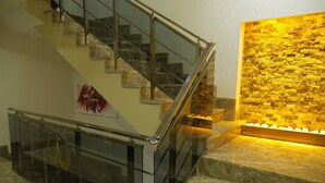 Un escalier moderne avec des rampes en verre et un mur en pierre dans lequel sont encastrées des lumières.