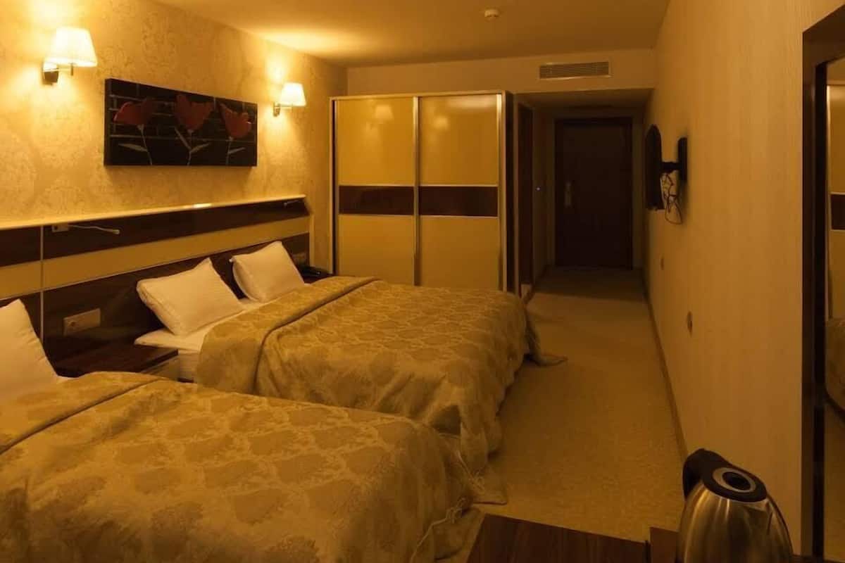 Ein Hotelzimmer mit zwei Betten, einem Bild an der Wand und einer Kaffeemaschine auf dem Nachttisch.