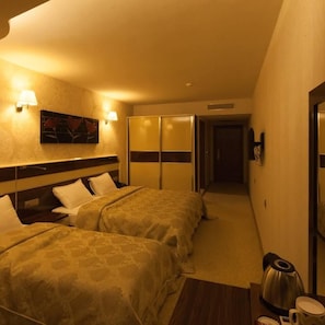 Une chambre d’hôtel avec deux lits, un tableau au mur et une machine à café sur la table de chevet.