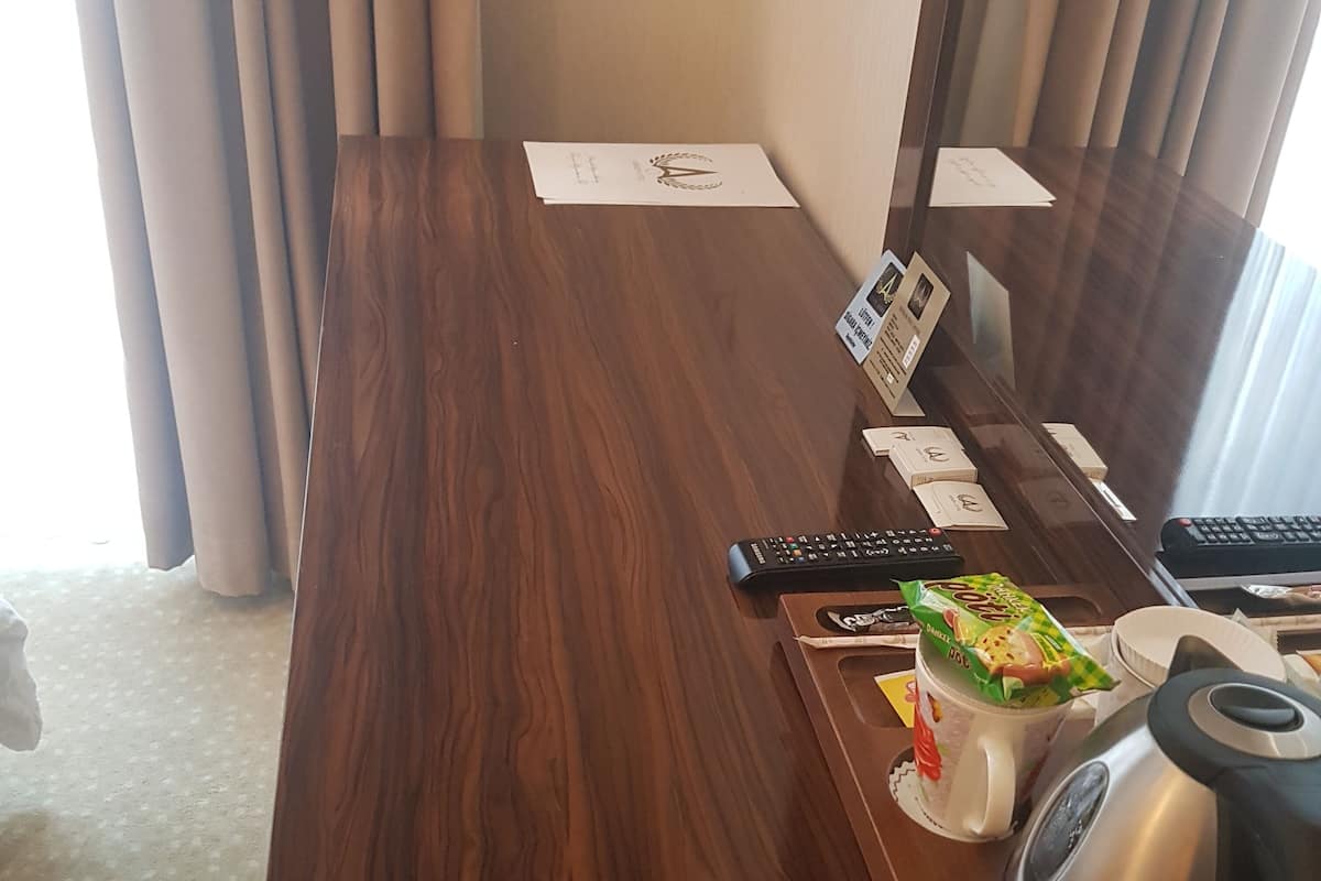 Ein Holztisch mit einer Fernbedienung, einem Wasserkocher und einer Kaffeetasse.