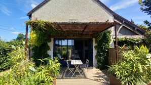 A house with a covered patio, a dining table and chairs, and surrounding greenery. - Studio*** 2 People Heated swimming pool between Châteaux de la Loire and Futuroscope (Rilly-sur-Vienne)