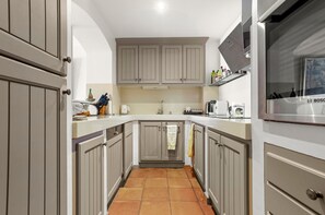 A narrow kitchen with grey cabinets, a tiled floor, and a Bosch microwave.