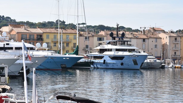 Un port de plaisance où sont amarrés plusieurs yachts, entouré de bâtiments à l’architecture traditionnelle.