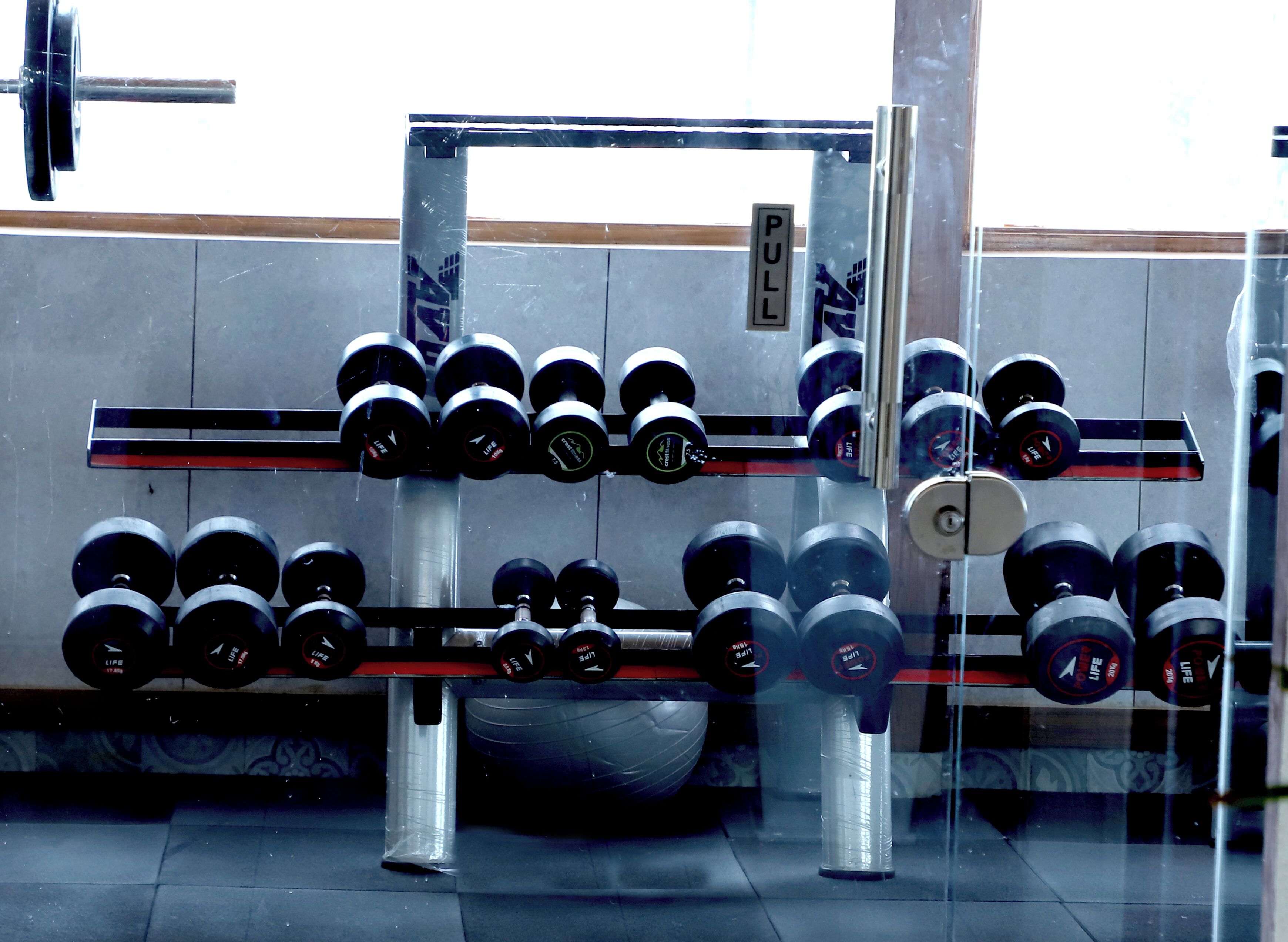 A weightlifting rack with multiple sets of dumbbells.