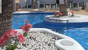 A swimming pool surrounded by palm trees and white buildings with balconies. - Azahara III Studio, Playa Las Vistas with wonderful seaview (Playa de la Américas)