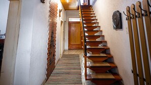 A staircase with wooden steps leading to a door, a wall-mounted clock, and a ski rack. - Cozy pension Sonnenhaus (Gundersheim)