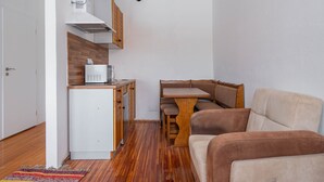 A compact kitchen with a microwave, wooden cabinets, and a dining area with a bench. - Cozy pension Sonnenhaus (Gundersheim)