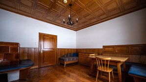 A room with wooden paneling, a herringbone floor, a bench, a sofa, a table, and a chandelier. - Cozy pension Sonnenhaus (Gundersheim)
