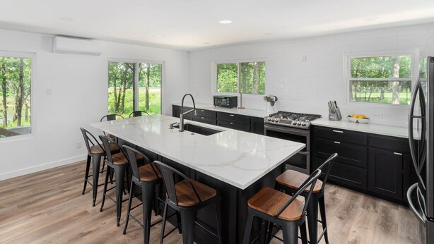 Una cocina moderna con una isla grande, armarios negros y vistas al exterior.