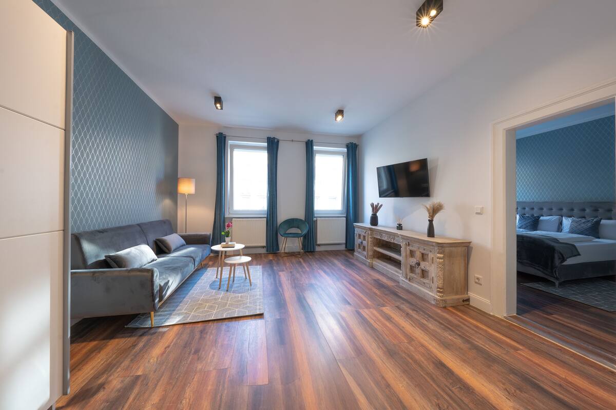 Un salon moderne avec un canapé, une petite table et un téléviseur fixé au mur.