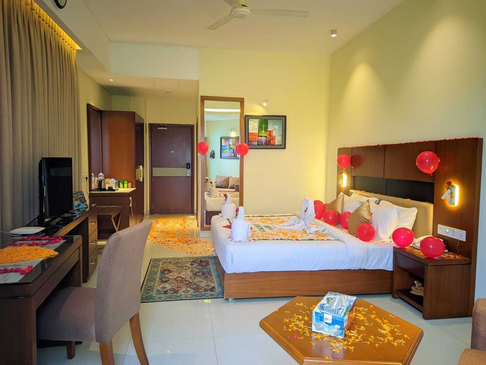 Quarto de hotel com cama, escrivaninha, televisão e banheiro visível por uma porta aberta.