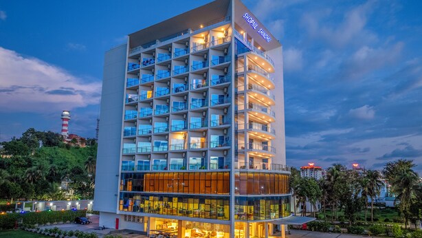Ein modernes Hotel mit mehreren Etagen, Balkonen und einem gut beleuchteten Eingang.