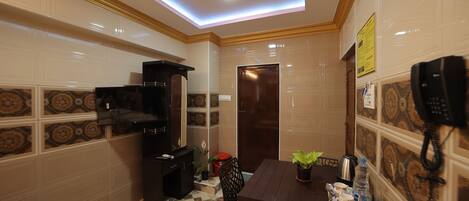 A compact hotel room with a dining area, a kitchenette, and a phone on the wall.