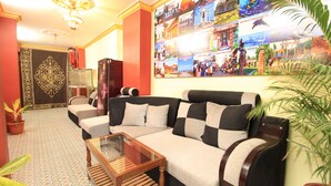 Una sala de estar con un sofá, una mesa de centro de vidrio y una pared decorada con un collage de fotografías de viajes.