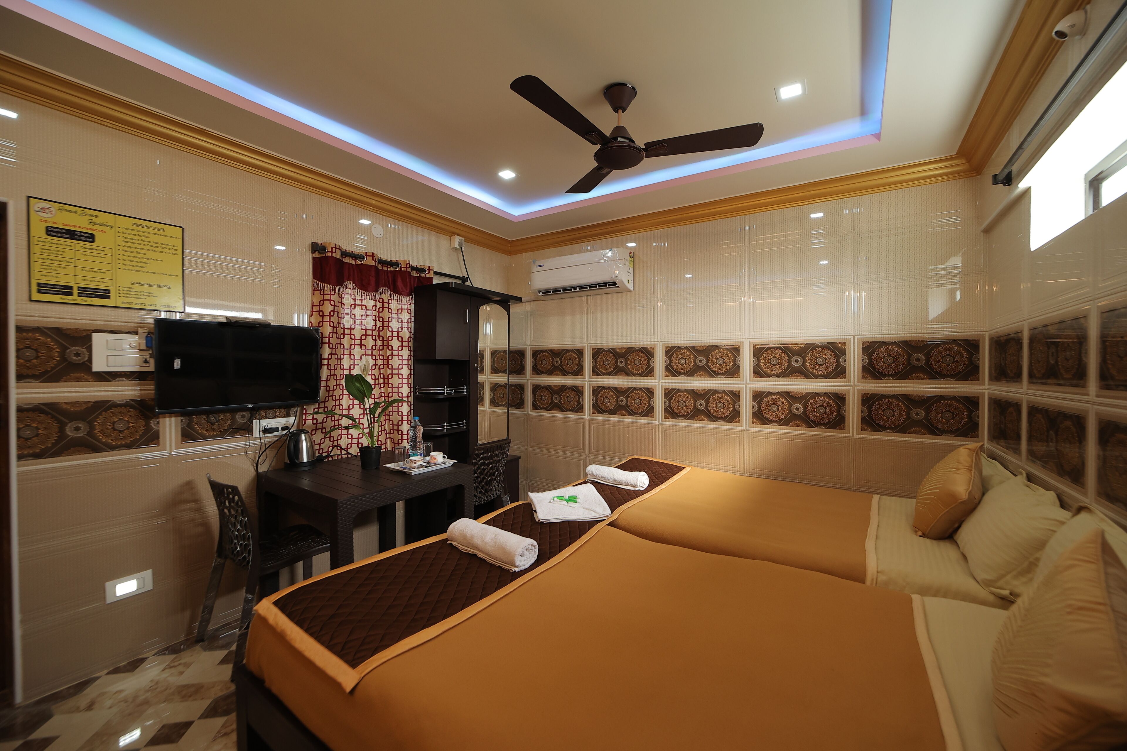 A hotel room with a bed, a desk, a television, and an air conditioning unit.