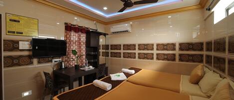 A hotel room with a bed, a desk, a television, and an air conditioning unit.